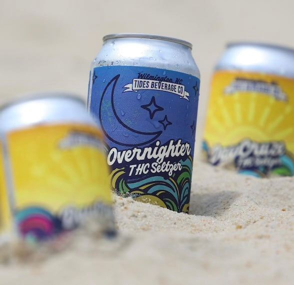cans of overnighter and daycruze thc seltzers in the sand at the beach