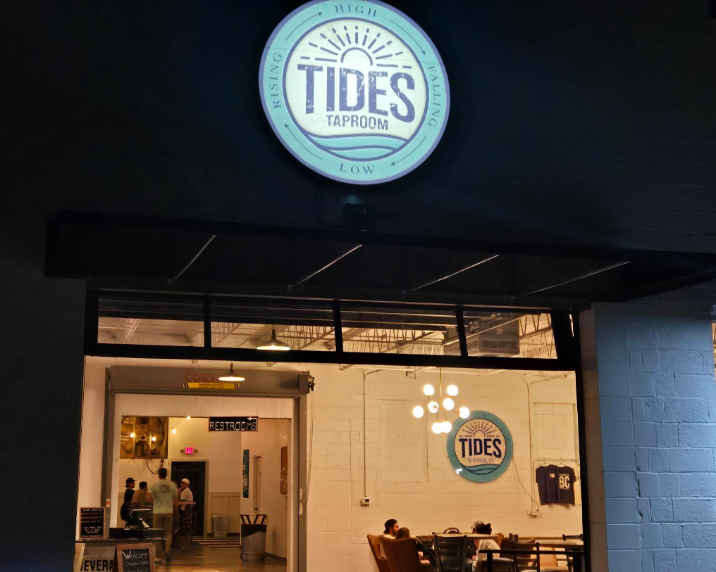 Tides Taproom entrance with illuminated logo on a dark night