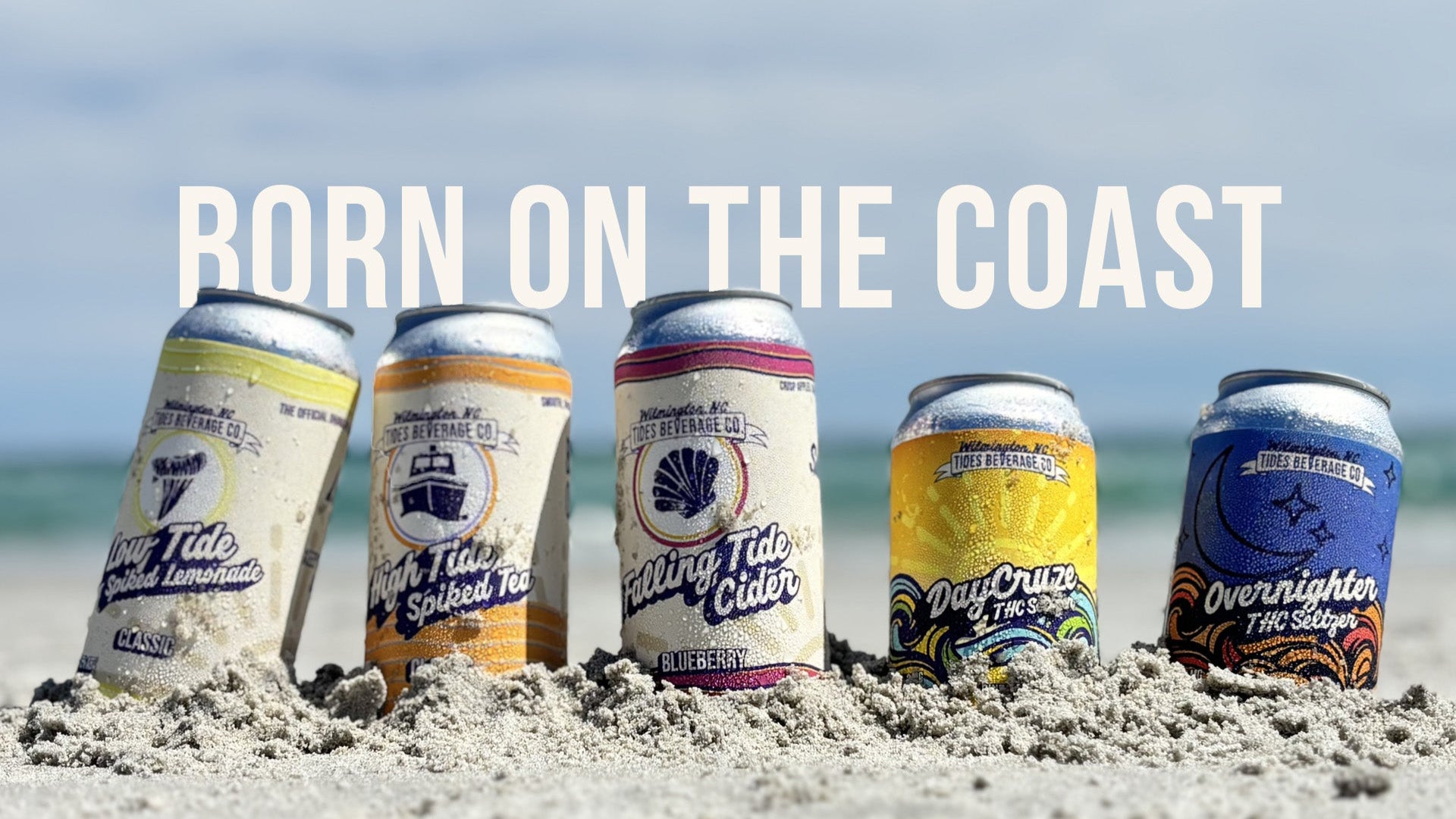 Wilmington NC Tides Beverage Co 5 cans flavor and variety on the sandy beach with "Born on the coast" above